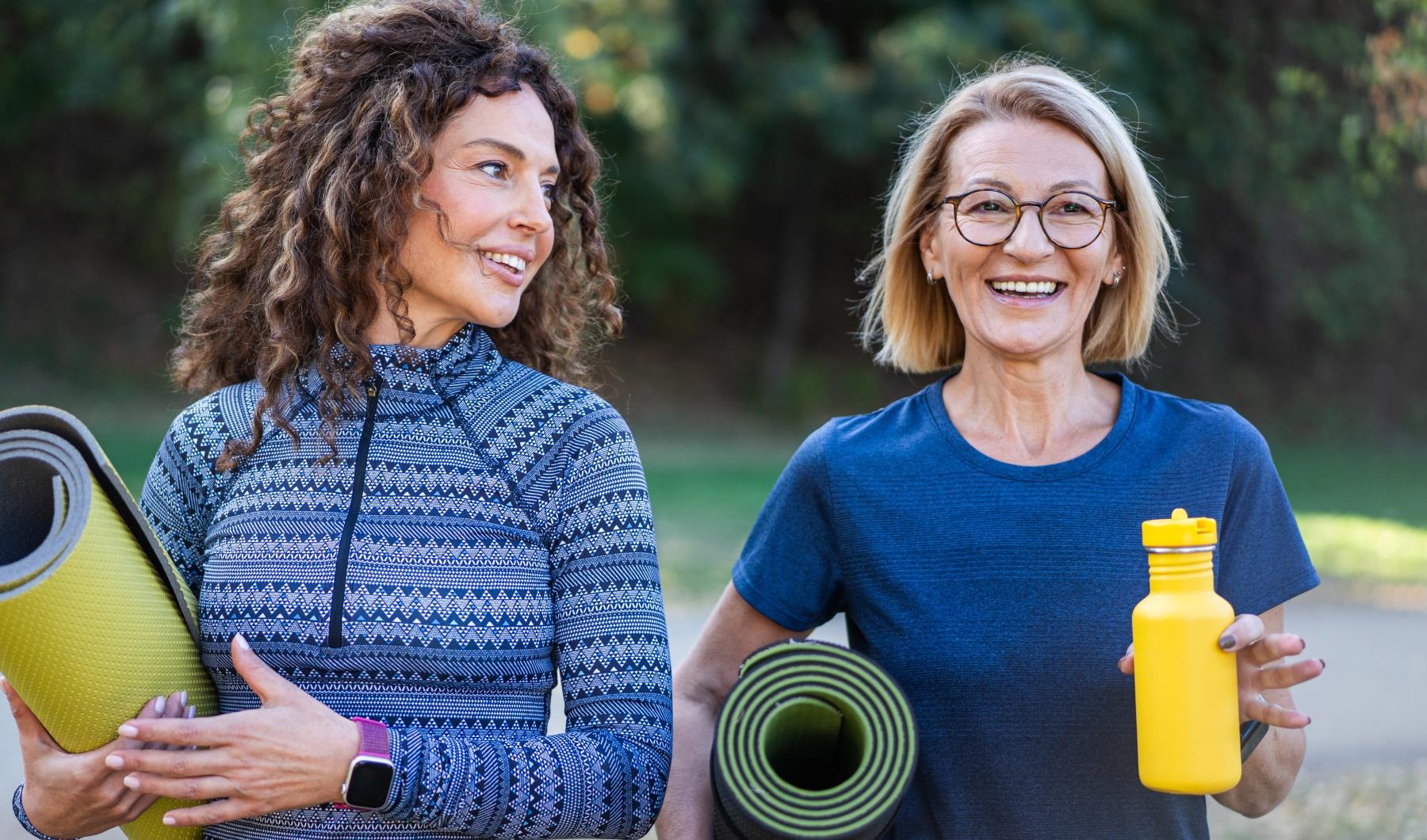 a couple of women holding yoga mats